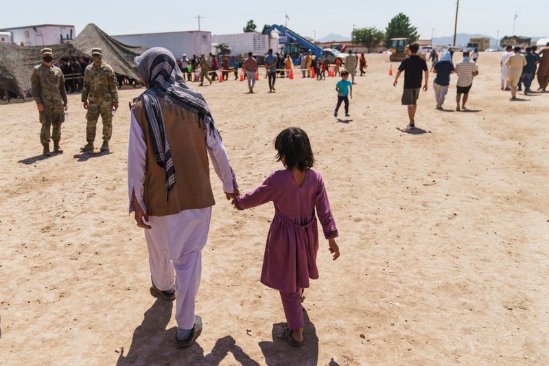 FILE - A man walks with a child through Fort Bliss' Doña Ana Village where Afghan refugees are being housed, in New Mexico, Friday, Sept. 10, 2021.