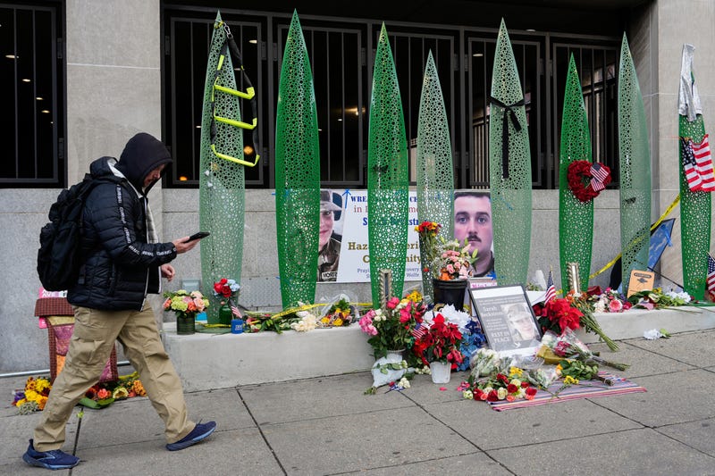 A person walks past a makeshift memorial for U.S. Army Spc. Sarah Beckstrom and U.S. Air Force Staff Sgt. Andrew Wolfe outside of Farragut West Station, near the site where the two National Guard members were shot, Monday, Dec. 1, 2025, in Washington.