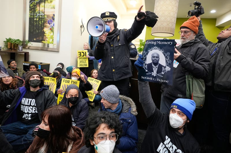 A police officer, top, makes an announcement about impending arrests during a sit-in in the lobby of a Hilton Garden Inn in New York, Tuesday, Jan. 27, 2026