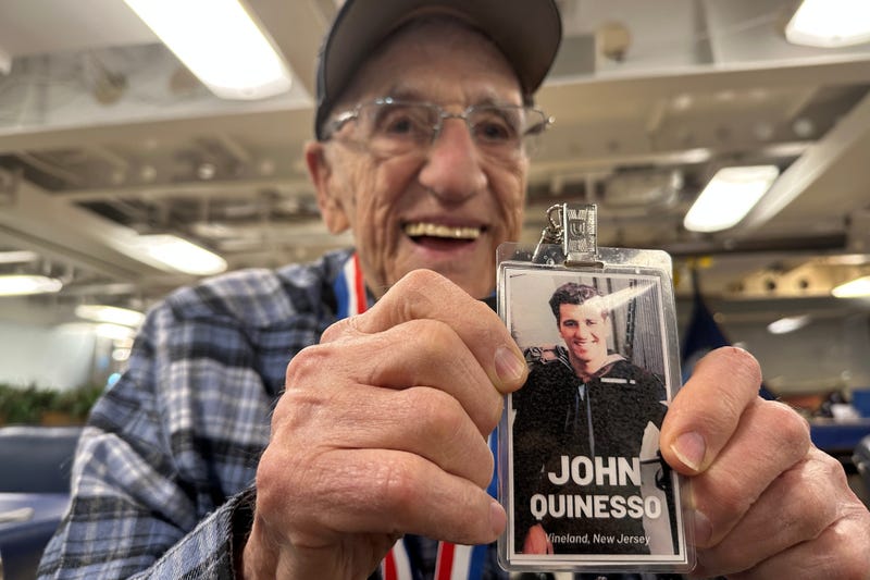 John "Johnny Q" Quinesso Sr, a WWII veteran, holds a photo of his younger self during his 100th birthday celebration on Thursday, Feb. 5, 2026 in Camden, N.J., aboard the Battleship New Jersey.