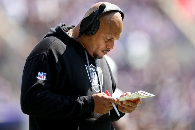 Raiders coach Antonio Pierce studies a chart on the sidelines.