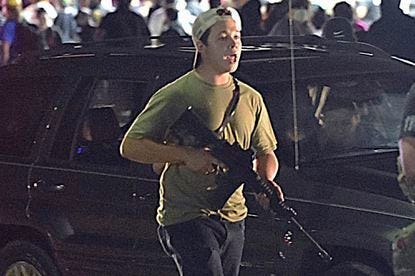 In an Aug. 25, 2020, photo, Kyle Rittenhouse carries a weapon as he walks along Sheridan Road in Kenosha during a night of unrest following the weekend police shooting of Jacob Blake.