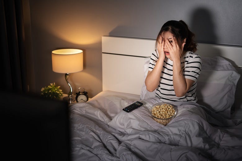woman covering her eyes while watching TV