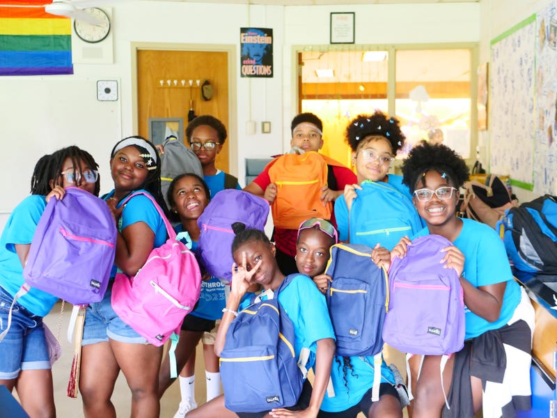 Students pose for a picture with their new backpacks ahead of the first day of school.