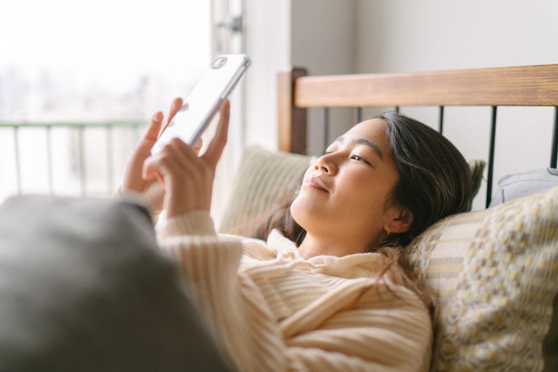 Woman laying in bed on cell phone