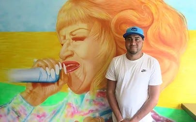 Owner of restaurant standing in front of mural