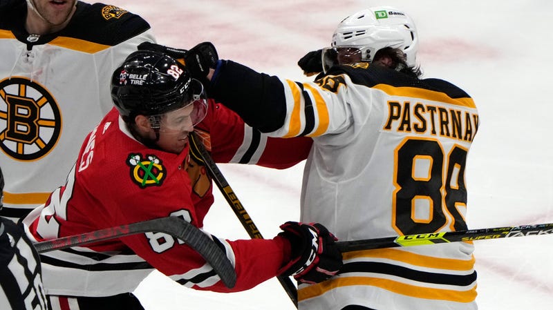 Blackhawks defenseman Caleb Jones (82) and Bruins right wing David Pastrnak (88) fight.
