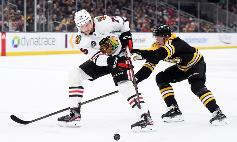 Blackhawks defenseman Alec Regula (75) tries to control the puck away from Bruins center Trent Frederic (11).