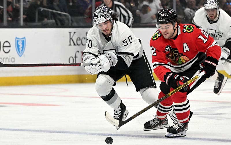 Kings defenseman Sean Durzi (50) and Blackhawks left wing Alex DeBrincat (12) chase down the puck.