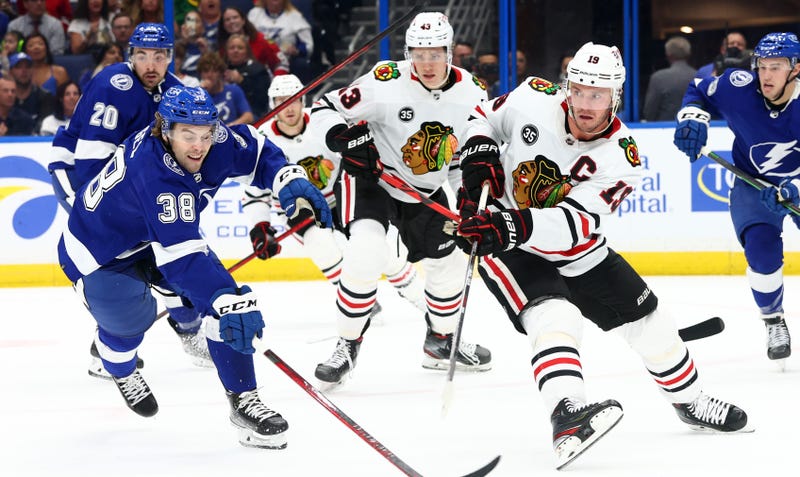 Blackhawks center Jonathan Toews (19) passes the puck as Lightning left wing Brandon Hagel (38) defends.