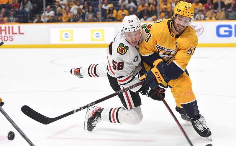Predators defenseman Roman Josi (59) clears a loose puck against Blackhawks right wing MacKenzie Entwistle (58).