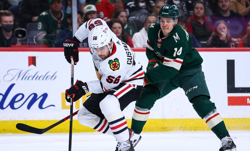 Blackhawks defenseman Erik Gustafsson (56) skates with the puck as Wild center Joel Eriksson Ek (14) defends.