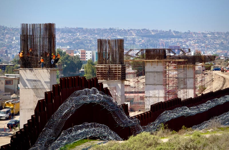 The US Border Fence between Mexico and California; background, construction on a new freeway in Tijuana, MX