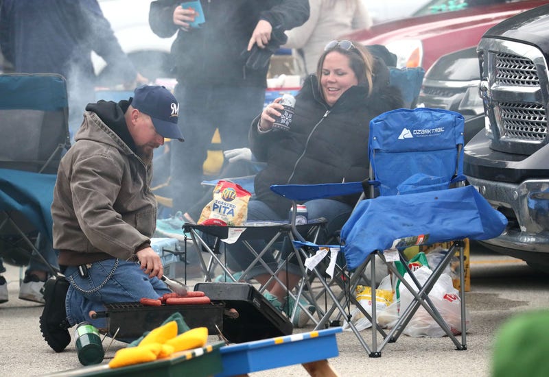 Justin Koss (left) and wife Lisa Koss (right) get their food cooked on a grill as they tailgate before the game. They are from Franklin. Brewers vs. Dodgers in NLCS playoff game 1 at Miller Park. Mjs Brewers13 Nws Sears 7