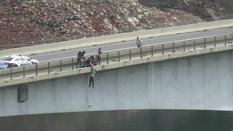 A Tuolumne County Sheriff’s corporal grabs an unidentified man through the railing on the Parrotts Ferry Bridge, holding him as he dangled for about 30 seconds before pulling him back to safety.