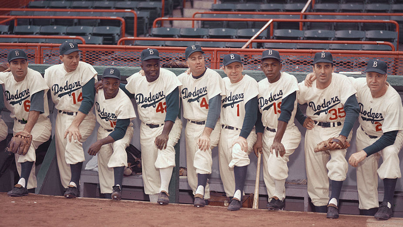 Portrait of members of the Brooklyn Dodgers baseball team pose in the dugout in 1954. From left, Americans Carl Furillo (1922 - 1989) (#6) and Gil Hodges (1924 - 1972) (#14), Cuban Sandy Amoros (1930 - 1992) (#15), and Americans Jackie Robinson (1919 - 1972) (#42), Duke Snider (#4), Pee Wee Reese (1918 - 1990) (#1), Jim Gilliam (1928 - 1978) (#19), Pete Wojey (1919 - 1991) (#35), and manager Walter Alston (1911 - 1984) (#24). 