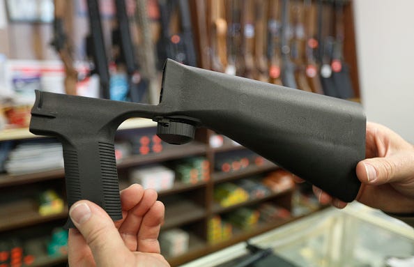 Two hands holding up a bump stock