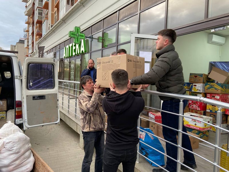 Vitalii Yaremchuk, director of Goncharenko Centre Chernivtsi, hands down a box of supplies to be delivered to displaced Ukrainians.
