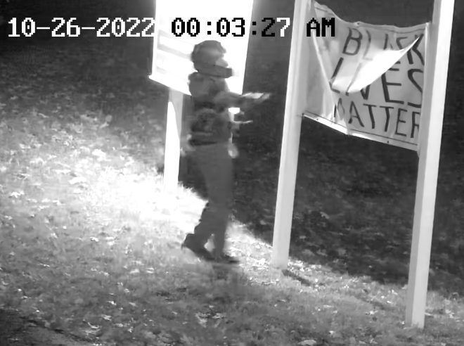 Surveillance images show a man in a motorcycle helmet damaging a "Black Lives Matter" sign outside a Unitarian church in Suffolk County in October