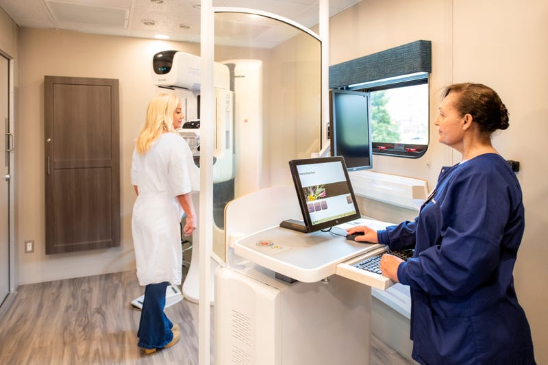 Carmen Aviles (right) demonstrates a mammogram on Virtua Health's mobile cancer screening bus.