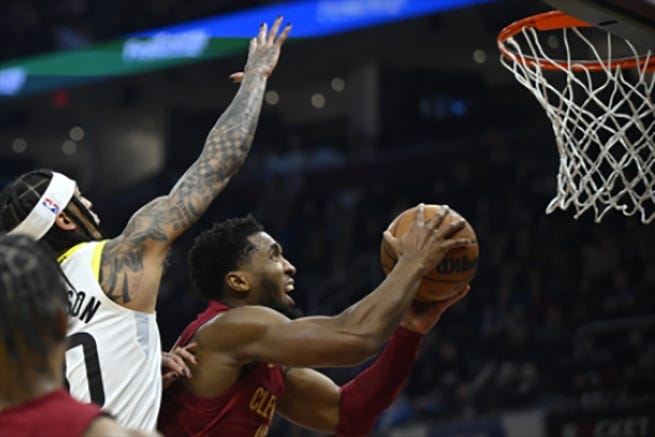 Cleveland Cavaliers guard Donovan Mitchell (45) shoots beside Utah Jazz guard Jordan Clarkson (00) in the second quarter at Rocket Mortgage FieldHouse.