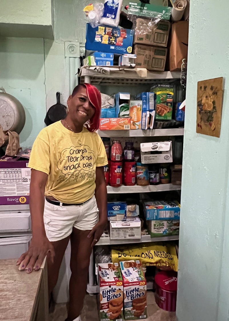 Champale Anderson stands in front of kitchen storage she uses to make hundreds of lunches for kids in her neighborhood each week