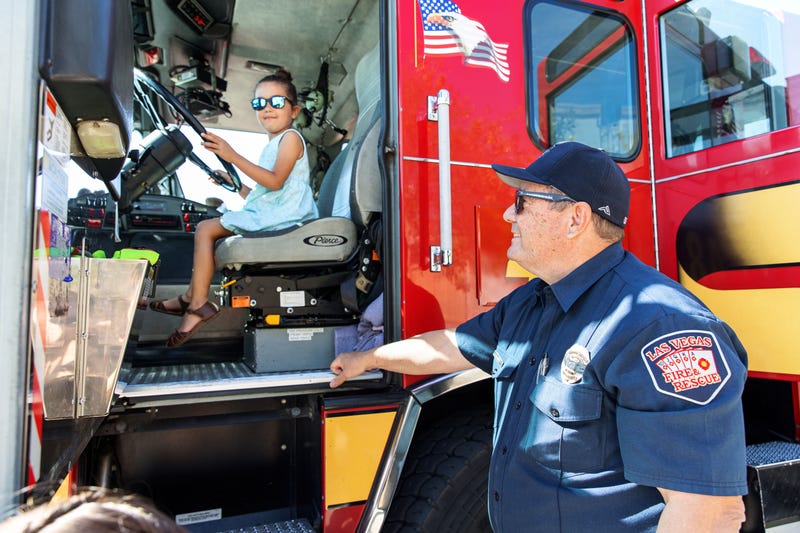 A young girl sits in the drivers' seat of a Las Vegas Fire and Rescue engine