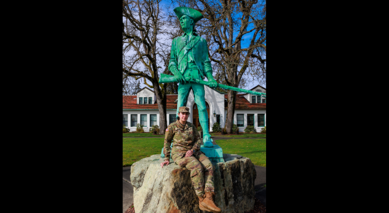 Spc. Rusha Adams, an information technology specialist with 1st Squadron, 303rd Cavalry Regiment sits next to the Washington National Guard Minuteman Statue on Camp Murray, Wash., Feb. 26, 2025.