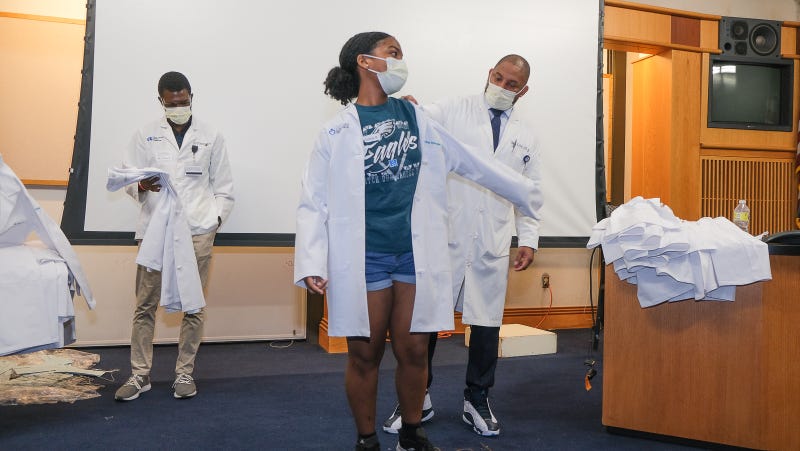 Dr. Thomas Butler calls students up one by one to adorned them with a brand new coat which they must wear throughout the week-long program.