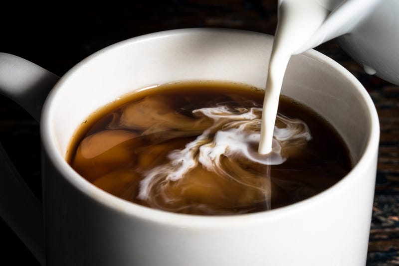 Creamer being poured into a cup of coffee