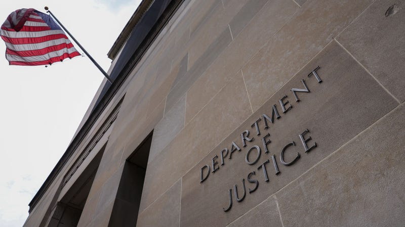The exterior of the Dept of Justice building, with an American flag flying