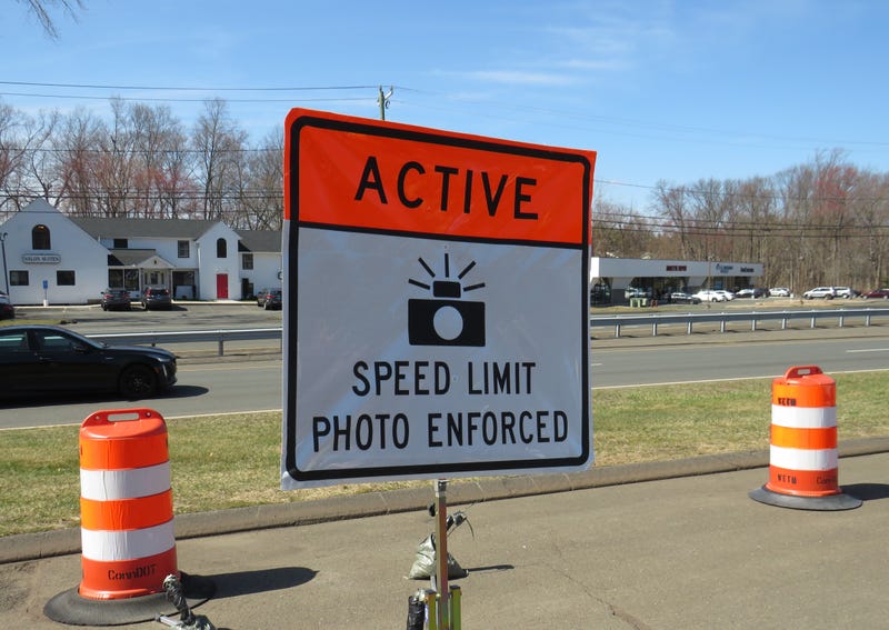 A sign to be posted at Connecticut highway work zones informing drivers that there's an SUV on scene with a camera and radar to monitor and ticket cars that speed through.