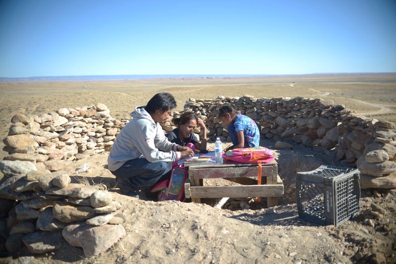 Milton T. Carroll and Wylean Burbank help their daughter Kyla with her schoolwork in a makeshift outdoor classroom