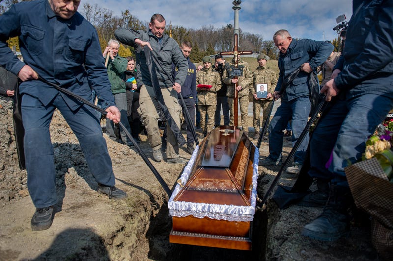 Men work together to bury a compatriot in Bucha, Ukraine.