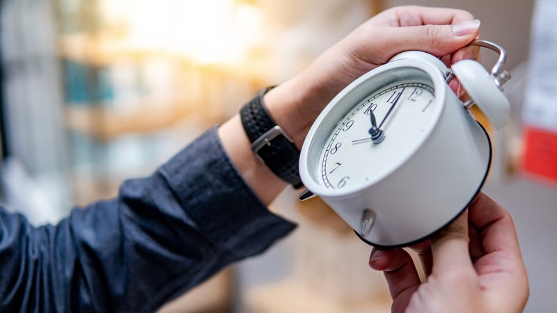 Male hand adjusting the time on white clock - stock photo
