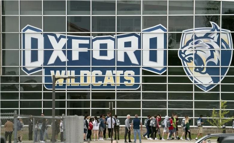 Students milling outside the front of Oxford High School. The "Oxford Wildcats" signage and logo are prominently featured in the photo.