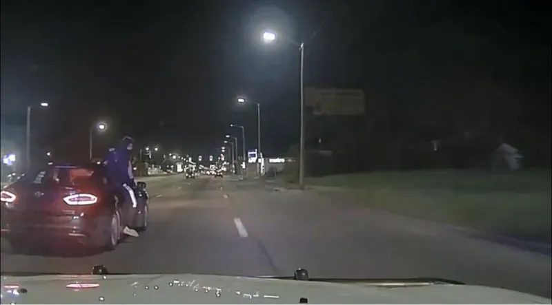 Suspect hanging out of the car