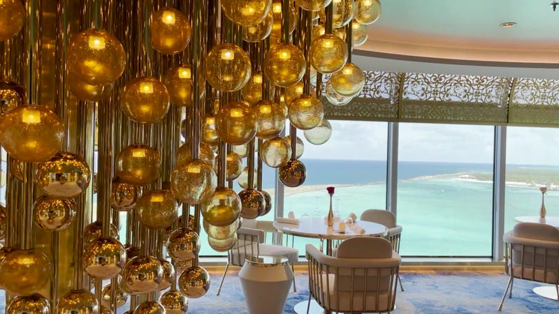 stunning golden light fixture in dining room with blue ocean in window