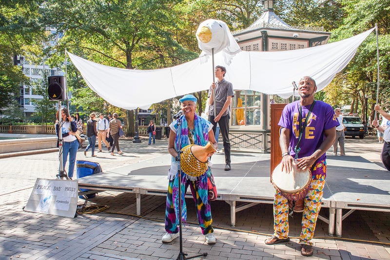 Musicians performing in Rittenhouse Square in front of a giant cloth dove.