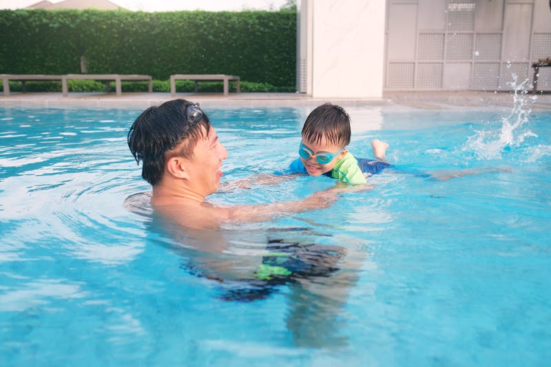 Father and son take a swimming lesson at pool