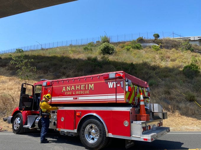 A brush fire erupted Monday on a hillside near the boundary separating Riverside and Orange counties, quickly burning three acres and snarling eastbound traffic.