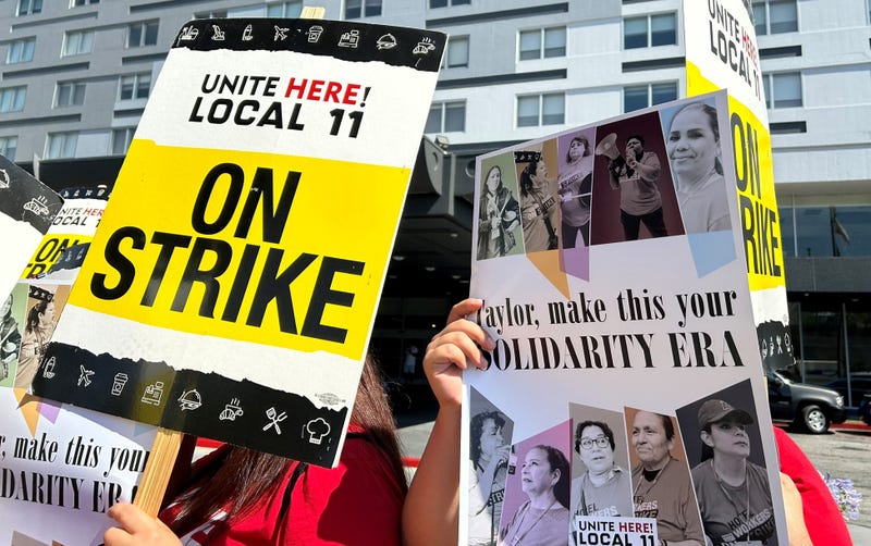picketers with signs that say unite here local 11 on strike and taylor make this your solidarity era