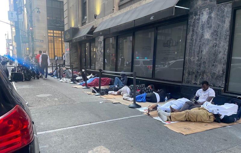 Migrant men sleep on the sidewalk outside the Roosevelt Hotel on Monday morning