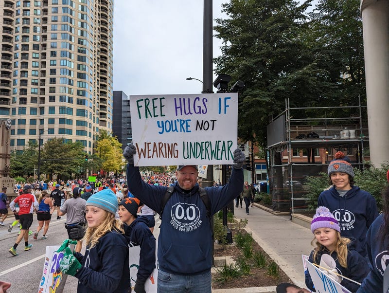 A Chicago Marathon supporter holds a sign that reads "Free hugs if you're not wearing underwear."