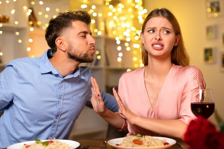 Woman rejecting man's kiss at dinner