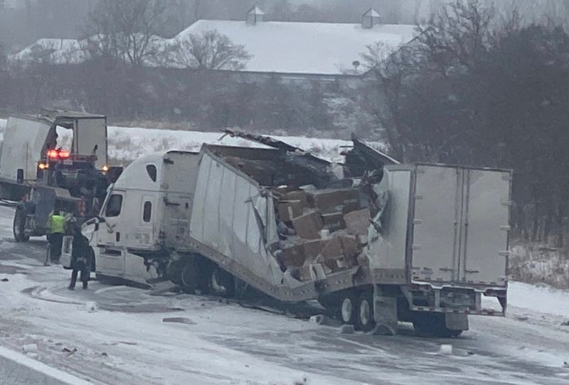 A semi-truck on I-75 with it's trailer ripped down the middle showing piles of cardboard boxes 