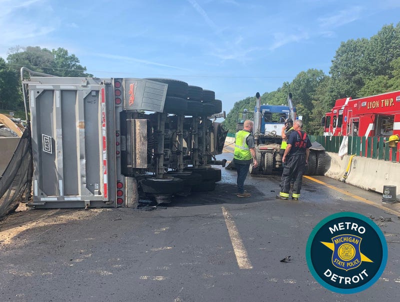 An overturned gravel hauler and hundreds of gallons of leaked fuel are hindering clean up efforts from a crash that injured two people on I-96 in Oakland County, officials say.