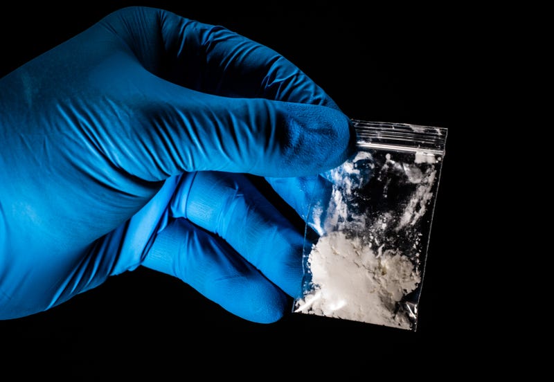 A technician holds a small bag of powdered fentanyl