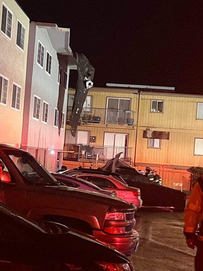 Part of the roof of the apartment building dangling before it was removed by firefighters. 
