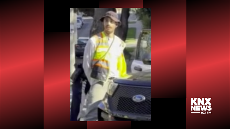 man with hands behind back leaning against cop car